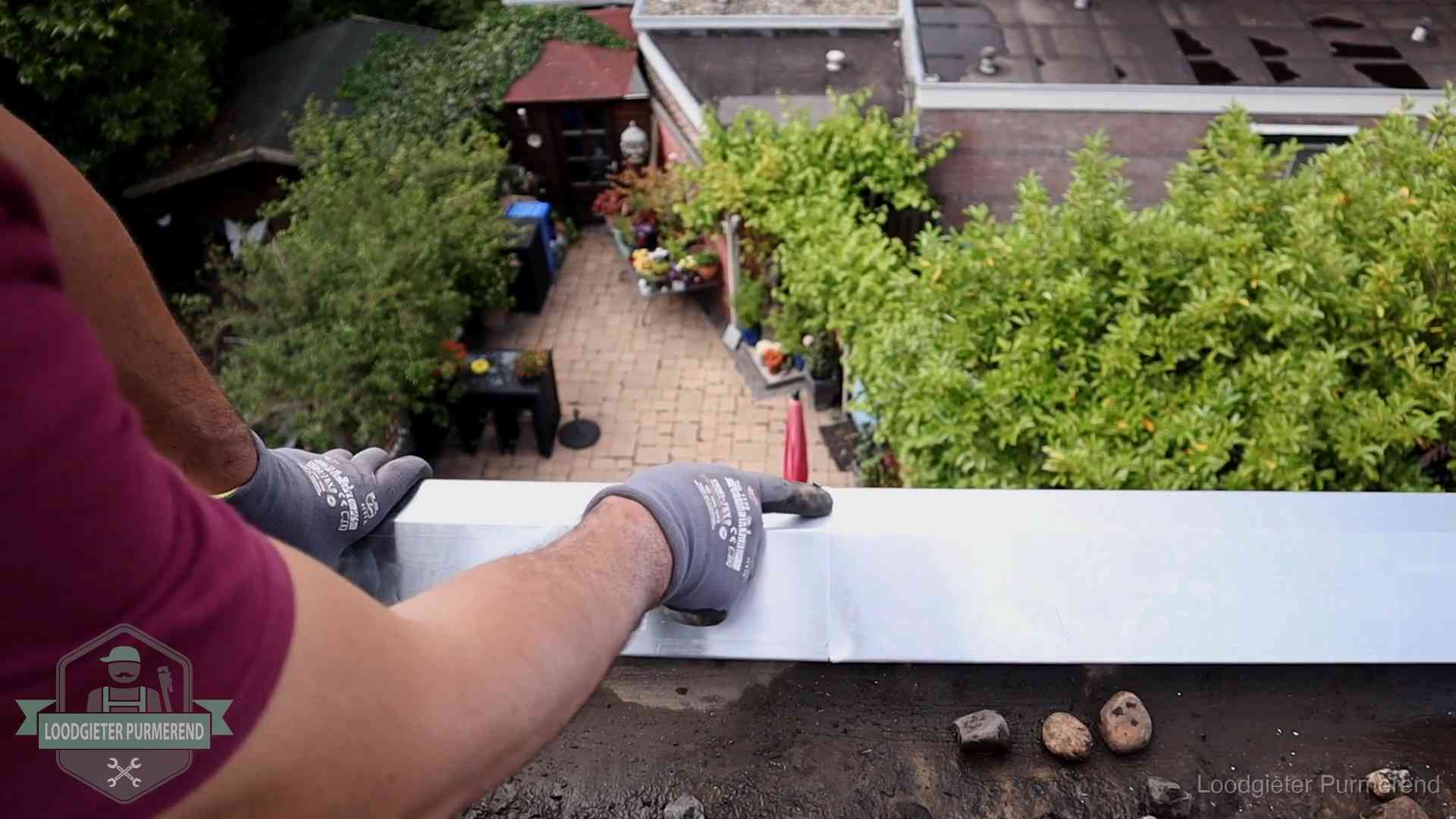 Vakman plaatst een daktrim op de dakrand van een woning in Purmerend