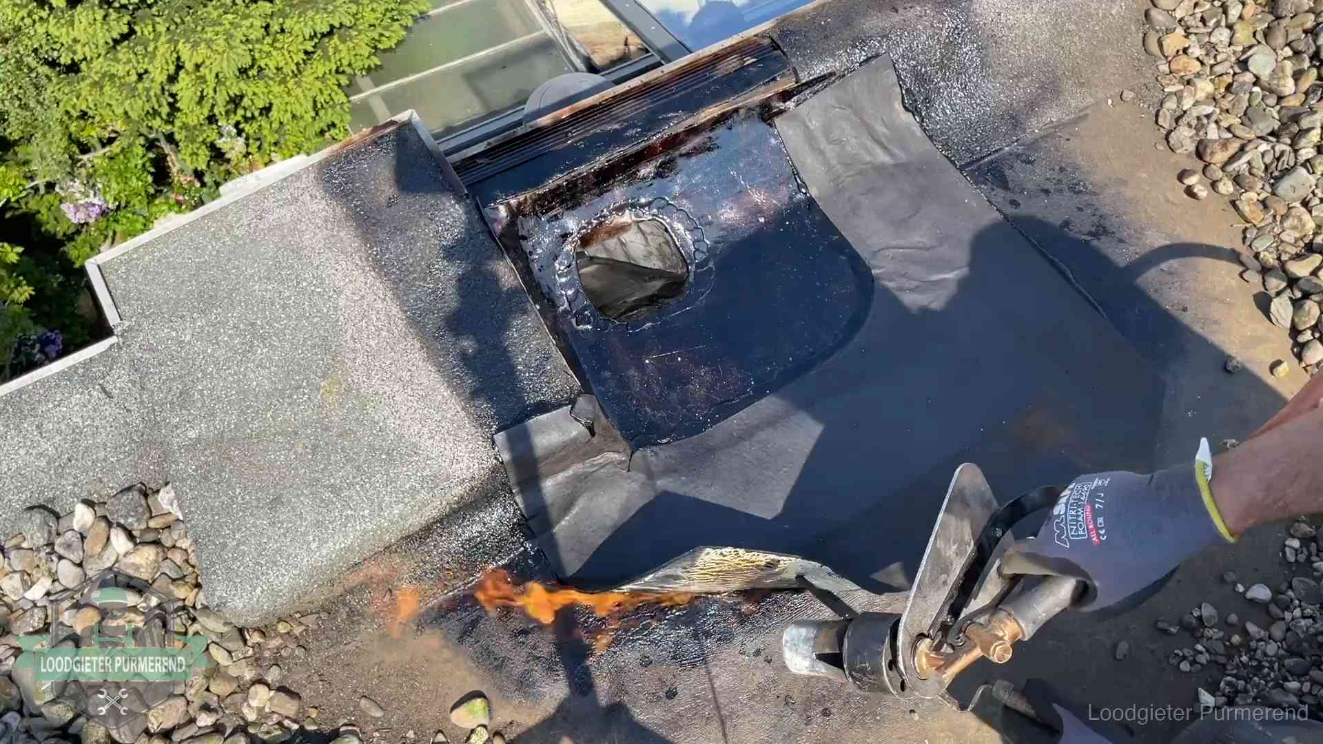 Dakdekker brandt bitumen rond een doorvoer tijdens een daklekkage-reparatie in Purmerend