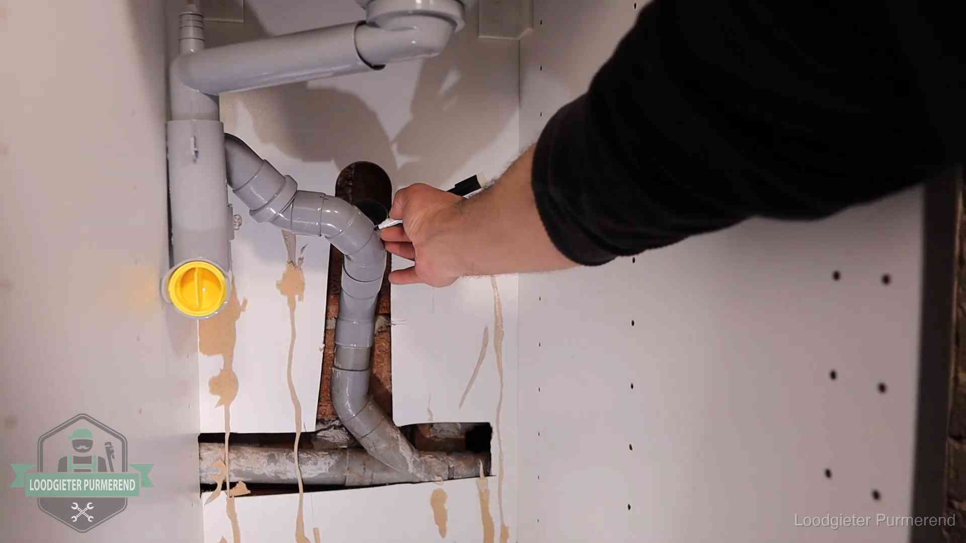 Loodgieter markeert een pvc-afvoerbuis onder een gootsteen in Purmerend
