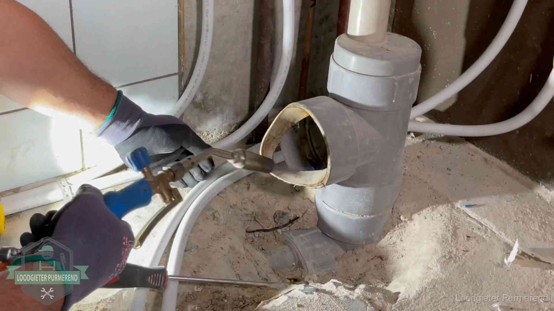 Loodgieter werkt met brander en messing kraanwerk aan leidingen in Purmerend