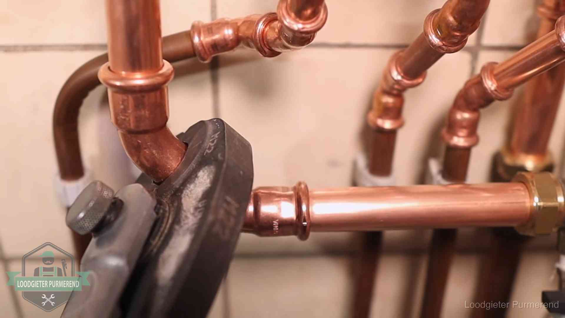 Persmachine perst een koperen fitting op nieuw leidingwerk in Purmerend