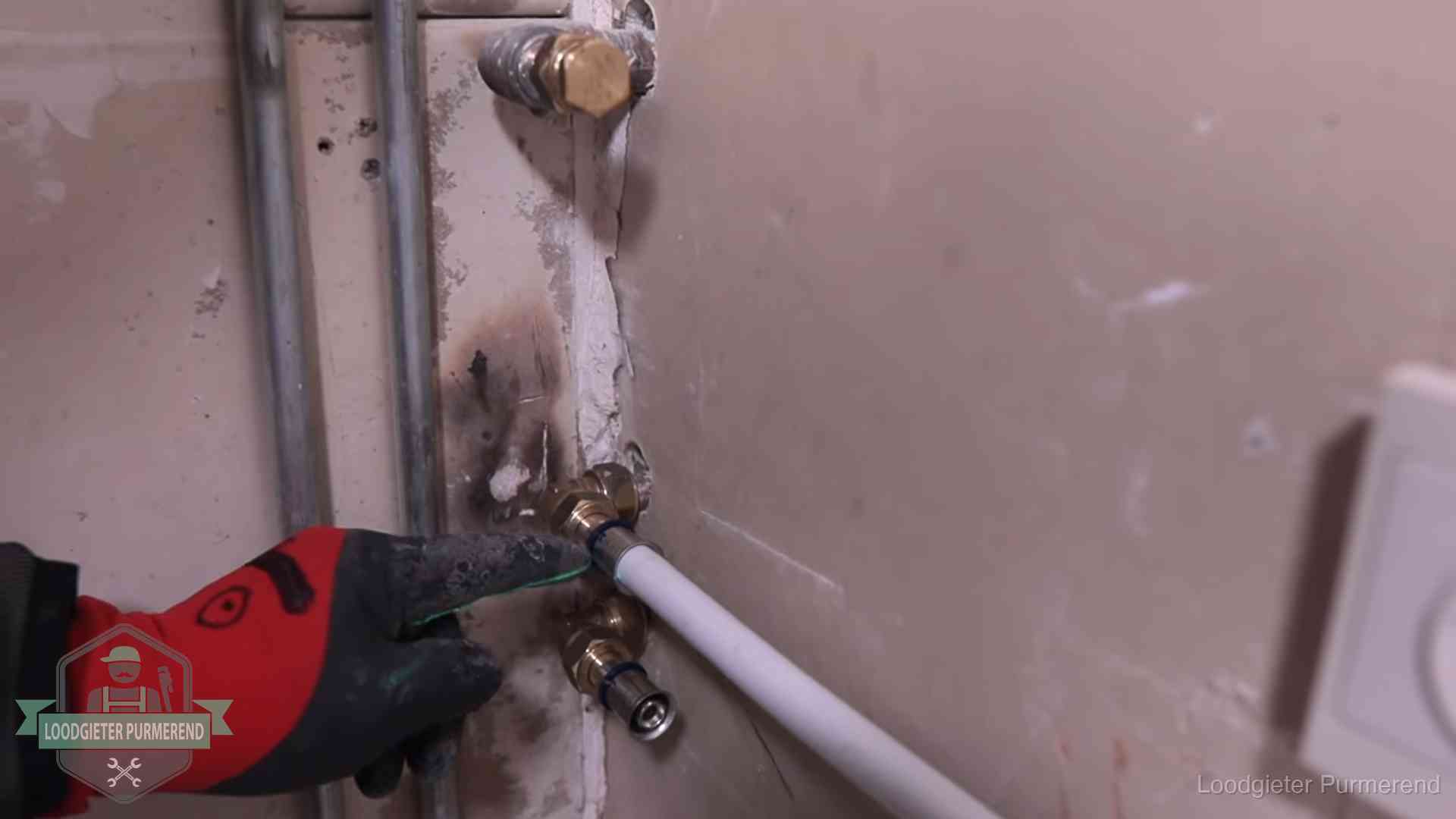 Loodgieter wijst de persfitting op nieuwe muuraansluitingen aan in een woning in Purmerend