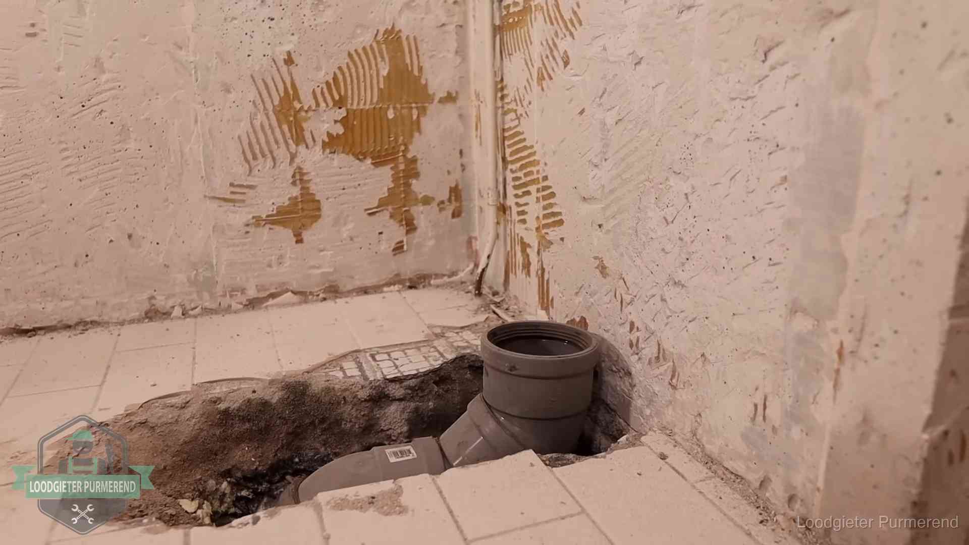Verzakt riool herstellen in Purmerend Opengebroken vloer met een nieuwe pvc-rioolbocht in een gegraven sleuf in Purmerend